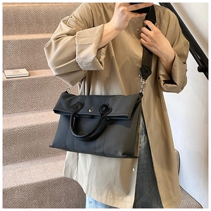 Detail of dark grey canvas tote featuring leather handles and a cat-paw stitch detail