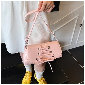 Detail of pink patent leather bag with silver eyelets and cross-tie ribbon design