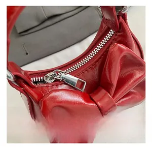 Nahaufnahme der roten Lackledertasche mit Schleifendekor und silbernem Metallreißverschluss