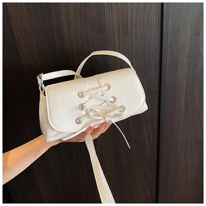 Close-up of white patent leather bag featuring silver eyelets and stylish lace-up details