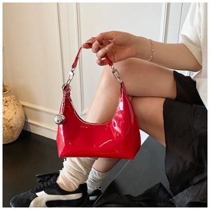 Détail du sac croissant en cuir verni rouge avec breloque boule argentée sur modèle