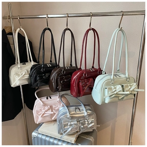 Detail view of colorful bow-accented bowling handbags hanging on a metal display stand