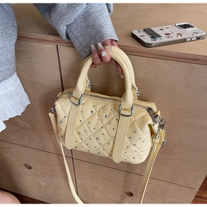 Detail of yellow quilted Boston bag with silver rhinestones and dual handles