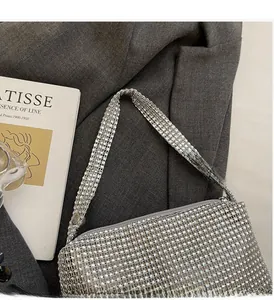 Detailed close-up of a silver rhinestone handbag placed on a blazer next to an art book