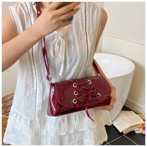Close-up of wine red patent leather shoulder bag with corset-style lace-up detail
