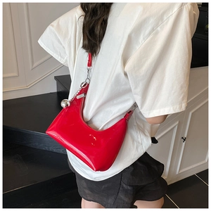 Détail du sac demi-lune en cuir verni rouge avec chaîne argentée et breloque sphérique
