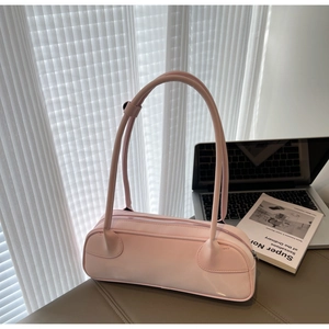 Close-up of pink barrel shoulder bag with dual straps on a minimalist desk setup