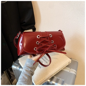 Dark red high-gloss shoulder bag with stylish lacing and bow details in a baguette style