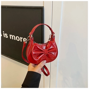 Detailansicht der roten glänzenden Handtasche mit Schleife, Tragegriff und Schultergurt