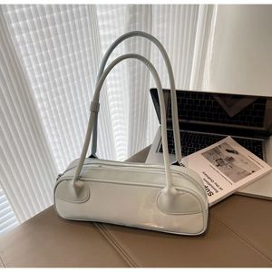Detail of mint green glossy baguette bag with long slim straps in a lifestyle office setting