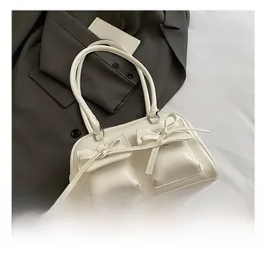 Detail of white vintage underarm bag featuring decorative bows and shiny faux leather texture