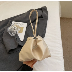 Detail of a creamy white satin handbag featuring elegant folds and a single handle design