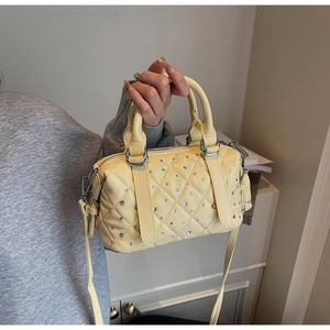 Detail of light yellow Boston bag featuring diamond quilting and shiny rhinestone accents