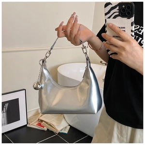 Détail du sac croissant argenté avec cuir verni miroir et pendentif boule métallique