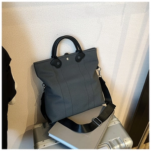 Detail of dark grey canvas tote bag with black leather handles and vertical stripes