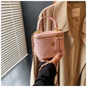 Pink quilted mini bag with gold floral logo and chain strap held by a person