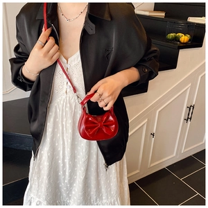 Detail einer roten Mini-Handtasche mit großer Schleife und glänzendem Finish am Modell