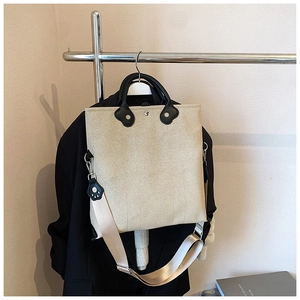 Detail of canvas tote bag with black leather handles and adjustable shoulder strap