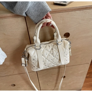 Detail of cream white quilted Boston bag with sparkling rhinestone accents and top handle