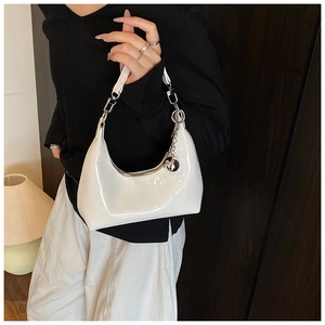 Détail du sac demi-lune en cuir verni blanc avec chaîne argentée et pendentif boule