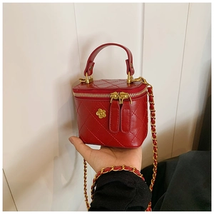 Close-up of red quilted leather mini bag with golden camellia and woven chain strap