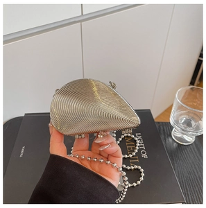 Makro-Detail einer silbernen Abendtasche in Muschelform mit metallischer Rippenstruktur