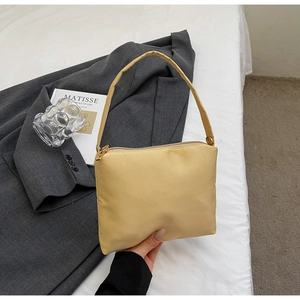 Detail of a cream yellow square handbag with gold zipper and smooth synthetic finish