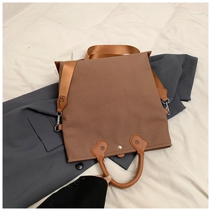 Detail of a brown canvas tote bag with unique cat paw leather accents and wide strap