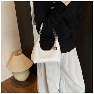 Détail du sac croissant en cuir verni blanc avec un charme sphérique en métal argenté