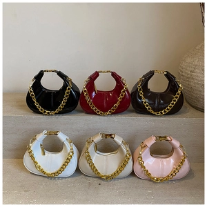 Detail view of mini dumpling chain bags in six colors displayed on stone steps