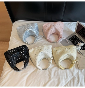 Top view of five colorful satin handbags with rhinestones on a white bed sheet