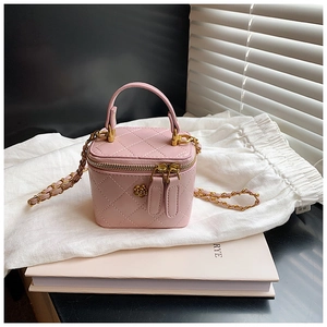 Close-up of pink quilted mini bag with gold flower buckle and chain strap on soft cloth