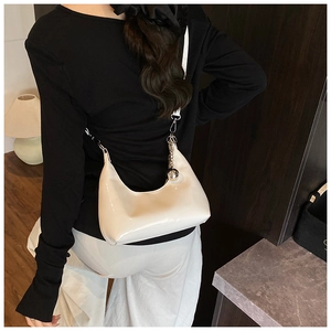 Sac hobo croissant en cuir verni beige avec chaîne porté par un mannequin