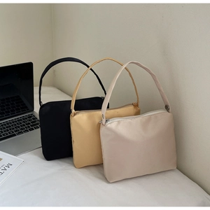 Chic small square handbags in black, yellow, and beige displayed on a stylish desk