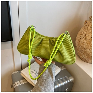 Detail of neon green pleated shoulder bag with thick knot strap in a lifestyle setting