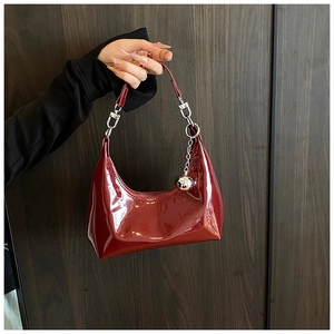 Détail du sac croissant en cuir verni bordeaux avec chaîne à boules et finition lisse