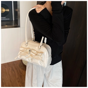 Detail of cream shoulder bag with bow pockets and glossy faux leather texture