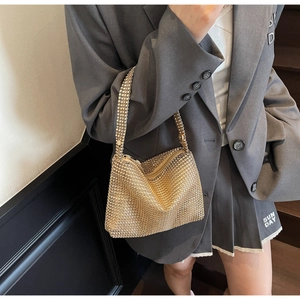 Detailed shot of sparkling gold rhinestone mesh handbag on a stylish charcoal blazer outfit