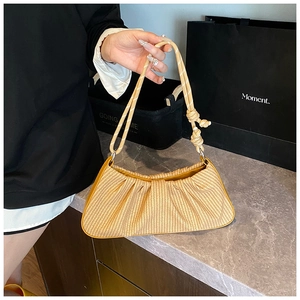 Detail of yellow woven cloud bag texture and handle hardware in lifestyle setting