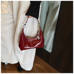 Détail du sac croissant en cuir verni bordeaux avec charm boule argentée et zip