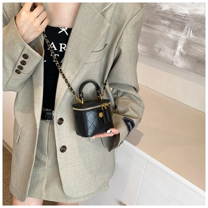 Detailed view of mini quilted leather crossbody bag with camellia hardware and chain strap