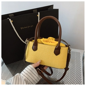 Detail of yellow straw tote bag with brown leather handles and drawstring lining