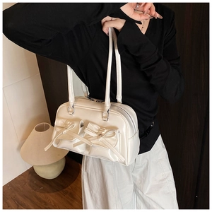 Detail of white glossy shoulder bag with bow accents and functional front pockets