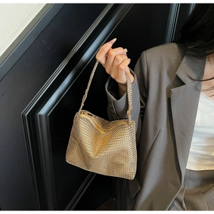 Close-up of gold mini square handbag with metallic mesh texture and chain handle