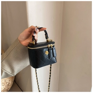 Detail of black quilted mini bag featuring gold camellia hardware and chain strap
