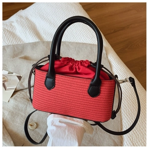 Detail of red straw woven bag featuring black leather handles and drawstring interior