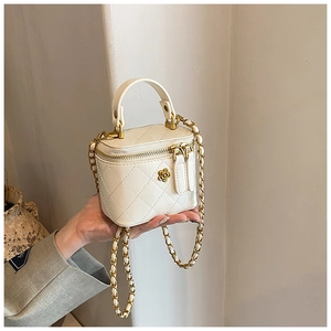 Close-up of mini white quilted leather bag with gold flower charm and chain strap