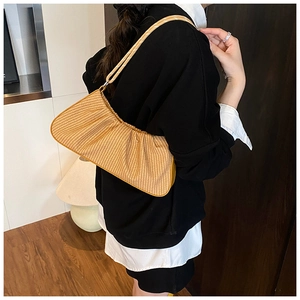 Detail of light brown straw cloud bag with elegant pleated texture worn on shoulder