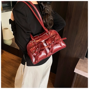 Detail of dark red bowling bag featuring decorative bows and glossy faux leather texture
