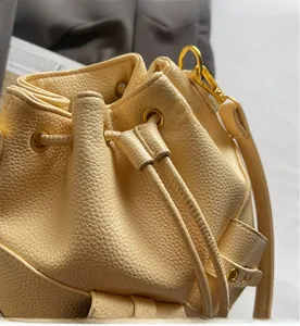 Close-up of cream yellow bucket bag showing lychee grain texture and gold metal eyelets